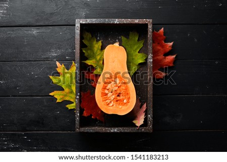 Fresh pumpkin in wooden box, autumn vegetables. On a black stone background. Top view. Free copy space.