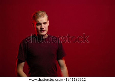 Emotional young man posing on a dark red background