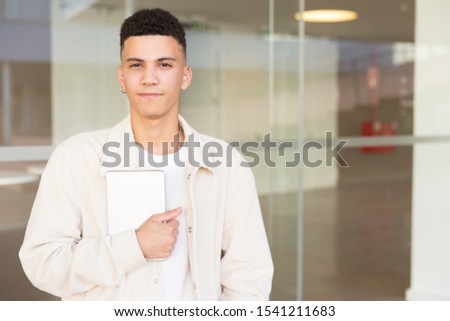Young man holding tablet pc and smiling at camera. Portrait of handsome happy young man holding digital tablet and looking at camera. Wireless technology concept