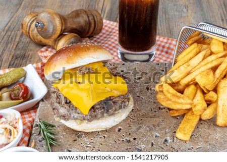 Delicious burgers with beef, tomato, cheese and lettuce and mayonnaise served on pieces of on a rustic wooden table of counter, with copy space.