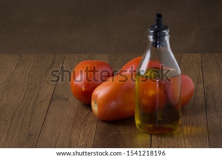 Olive Oil Oil on wooden table with red tomatoes in the background.