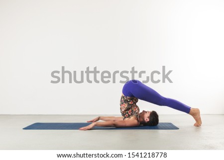 woman in plow position poses yoga on a white background