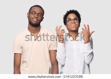 Head shot bored African American man listening to excited smiling woman, bad conversation, beautiful girlfriend talking to boyfriend, friends wearing glasses standing isolated on grey background Royalty-Free Stock Photo #1541223188