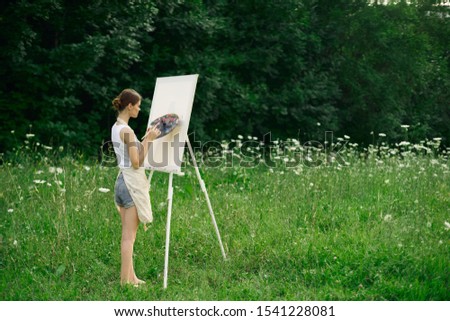 young beautiful smiling cheerful woman outdoors easel with paints