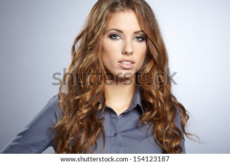 Portrait of a beautiful young business woman standing against grey background 
