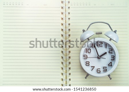 Back to school concept. Alarm clock on notebook  background