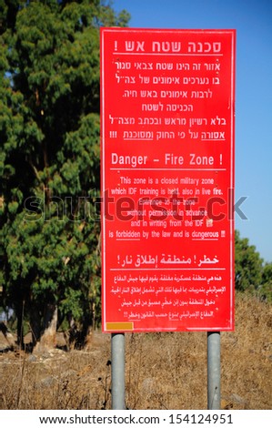 Red signboard warning about closed fire training zone. Golan Heights. Israel.