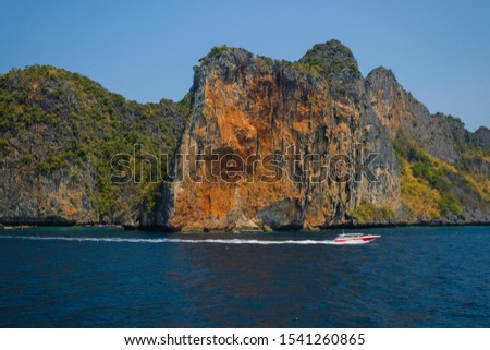 Boat on the background of the rainforest on the cliff.
