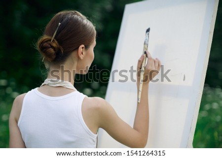 young woman on canvas paints a picture with paints