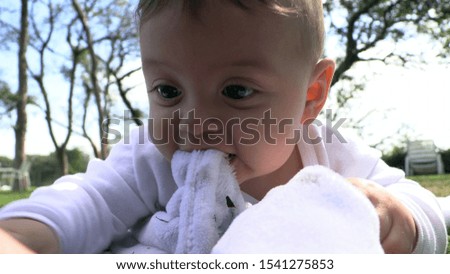 
Baby toddler playing in outdoor park biting blanket