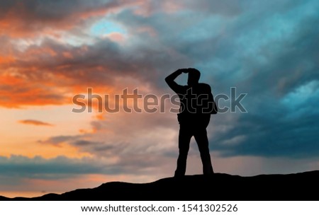 travel, tourism, hike and people concept - traveler with backpack standing on edge of hill and looking far away over sunset background