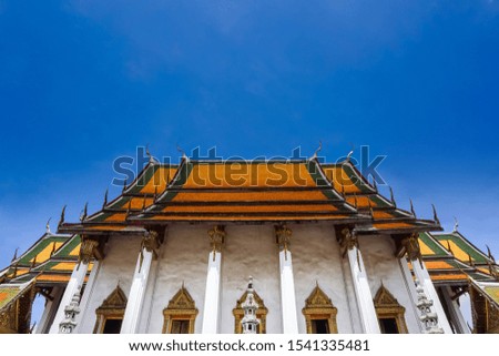 Buddhist temple hall of Wat Suthat Thep Wararam under clean blue sky in Bangkok, Thailand