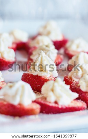 Stuffed strawberries filled with cheesecake filling made with whipped cream and cream cheese. Sprinkled with graham cracker crumbs. Selective focus with blurred foreground and background.