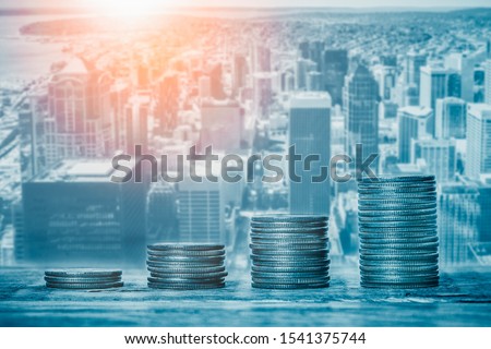 Stacks of coins with cityscape or skyline in the background. Financial growth, real estate sector prices, municipal budget or city funds, economy or banking concepts. Royalty-Free Stock Photo #1541375744
