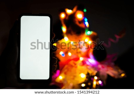 Portrait of a hand holding a smartphone at night and bokeh LED lights