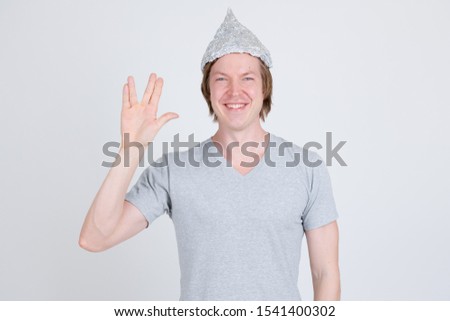Happy young man wearing tin foil hat as conspiracy theory concept showing Vulcan salute in Star Trek