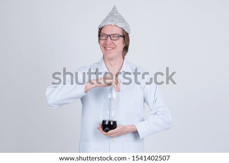 Happy young man doctor with tinfoil hat thinking while holding bottle of soda
