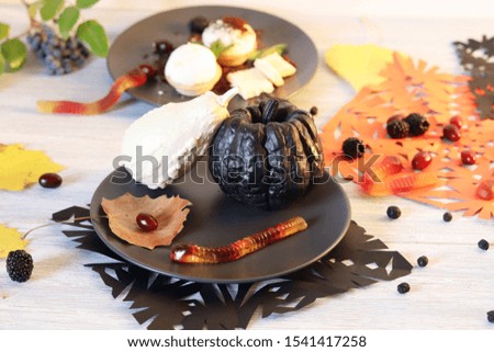 Halloween food, dessert with chocolate, pumpkins, ice cream and jelly worms on a wooden table