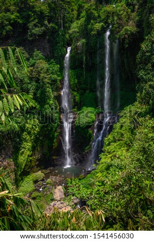 Aerial view on the Sekumpul waterfalls with many tourists around in the middle of the rain forest, one of the most famous popular and beautiful destinations while travel to Bali island in Indonesia.