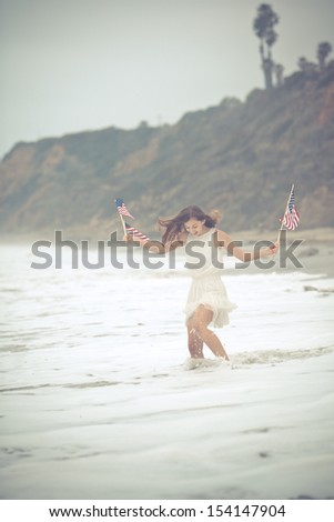 Beautiful Teen Girl with American flags walking on the Beach in Malibu