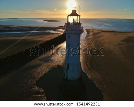 Sun setting behind beach lighthouse