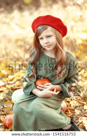 Little cute girl sitting in the autumn forest on ripe pumpkins. Autumn mood. Thanksgiving Holiday Concept.