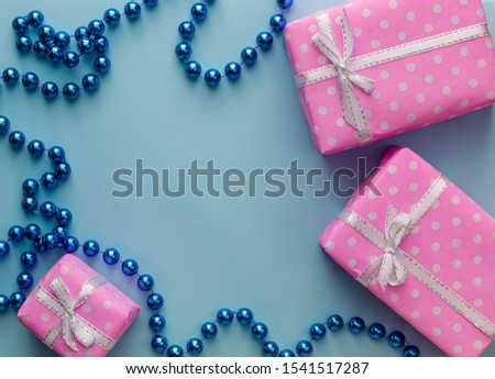 Gift or present pink boxes with ribbon on pastel blue background. Flat lay composition for holidays greetings. Copy space