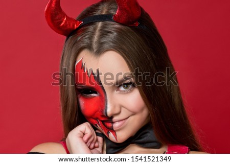 Devil. Funny imp with red horns and black bow tie at Halloween party. Halloween makeup. The devil costume.