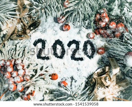 Christmas composition of fir branches, bells, snow and mountain ash with numbers 2020
