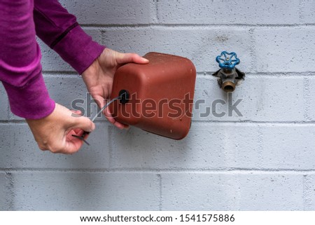 Winterization, woman’s hands installing foam and plastic faucet cover to prevent pipes freezing, on a blue gray painted brick wall
 Royalty-Free Stock Photo #1541575886