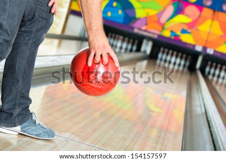 Young man in bowling alley having fun, the sporty man holding a bowling ball in front of the ten pin alley