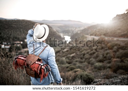 young boy with hat and backpack traveling through nature and taking pictures