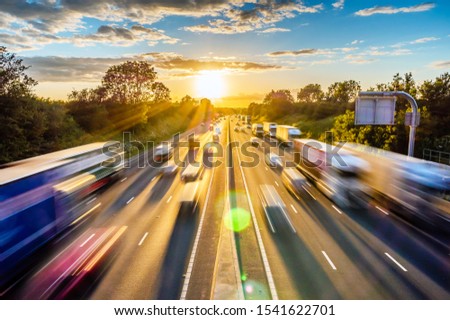 heavy traffic moving at speed on UK motorway in England at sunset Royalty-Free Stock Photo #1541622701