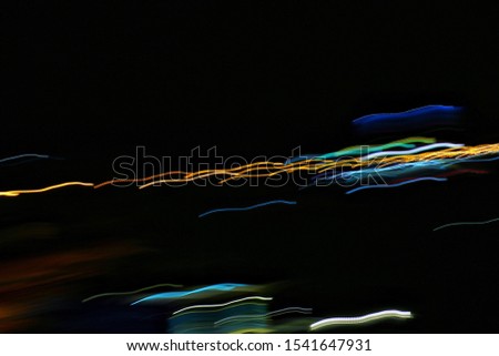 Long exposure, light painting photography. Vibrant streaks of electric colored light against background.
