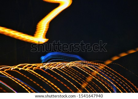 Long exposure, light painting photography. Vibrant streaks of electric colored light against background.