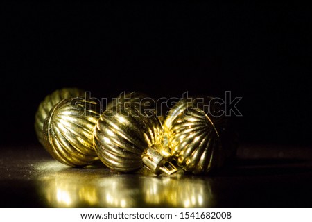 Golden bauble ornaments photographed in a studio with black backdrop and spotlight.