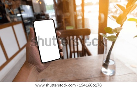 Mockup image blank white screen cell phone.men hand holding texting using mobile on desk at coffee shop. background empty space for advertise text.people contact marketing business and technology 