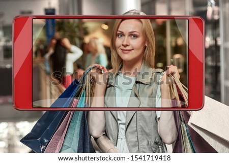 Beautiful blonde woman with shopping bags in smartphone frame