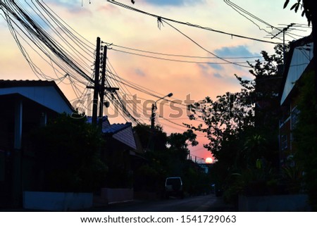 Landscape of sunset in silhouette image was taken at the village with electric lines.