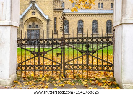 Autumn view. Metal gate on the background of autumn leaves and the cathedral.