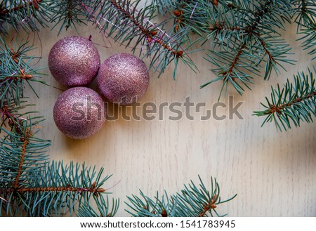 Branches of blue spruce and Christmas balls on a light wooden background.Copy space. View from above. Flat lay.