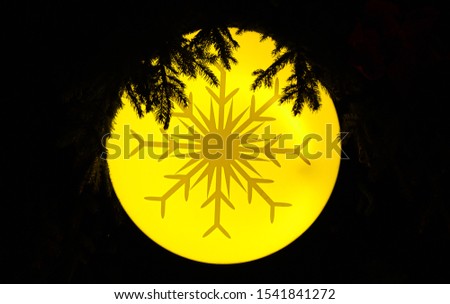 A snow flake design on an yellow christmas tree ornament