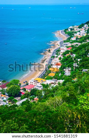 Famous coastal city in Vietnam Vung Tau, shore view. Houses on a hillside in dense greenery. Vertical photo 