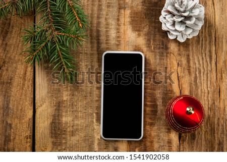 Mock up blank empty screen of smartphone on the wooden background with colorful holiday's decoration and gifts. Copyspace, negative space for your advertising. 31 of December, New Year concept.