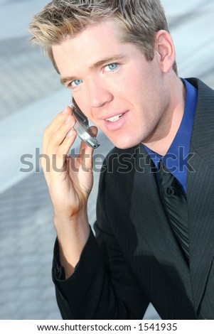 Blond hair blue eye business man is holding cell phone next to his ear
