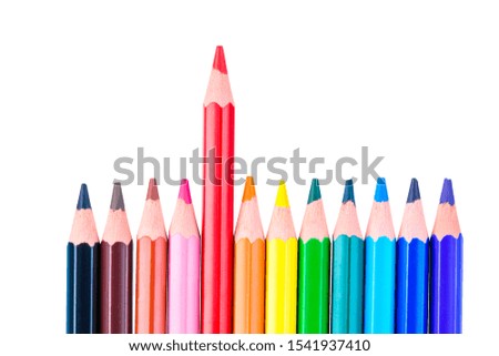 concept photo of a red pencil stand out from a row of colored pencils on a white background isolated