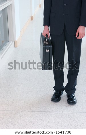 Business man wearing black suit with black shoes is holding his black briefcase