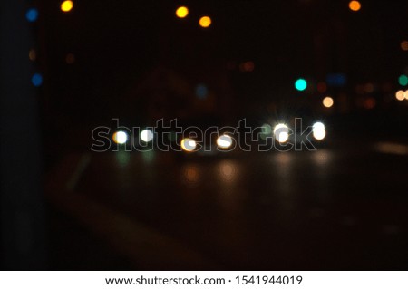 Background. The subject is out of focus (no sharpness). On the night, city road go three cars. For design.