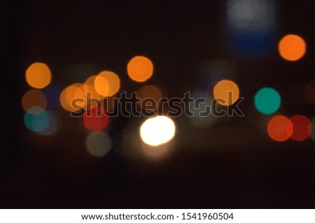 Background. The subject is out of focus (no sharpness).  City, night road. Lights are shining, traffic lights are on, a car is going .For design.