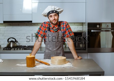 Young man sits in the kitchen next to a table with flour.